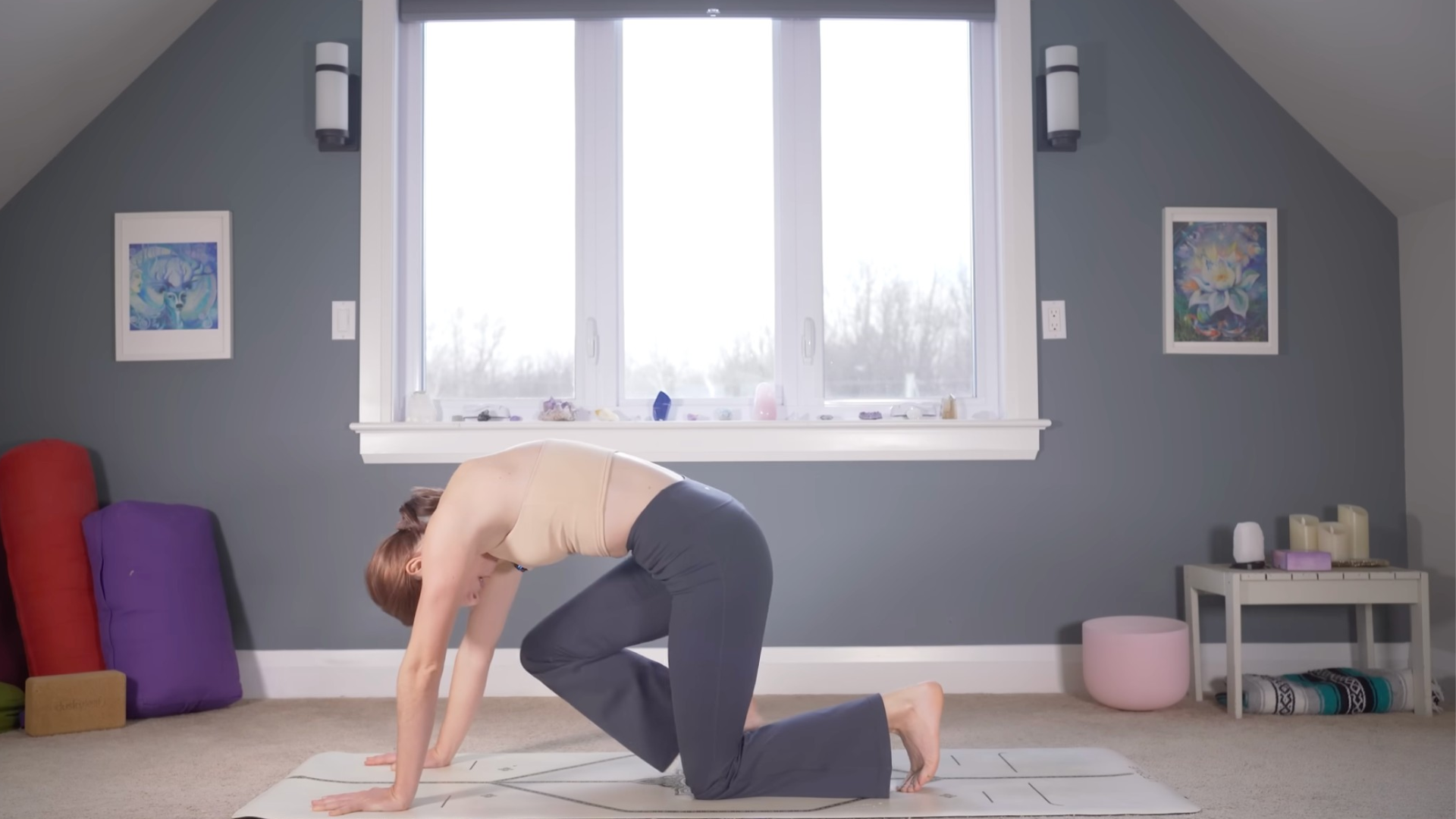 Woman on hands and knees drawing her right knee toward her nose practicing yoga for strength