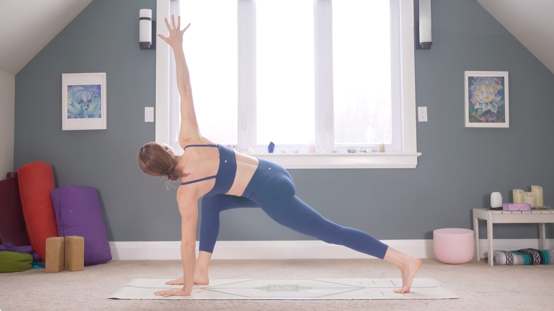 Woman in a lunge with her back knee lifted and her left hand on the mat while she twists to the right and reaches her right hand toward the ceiling