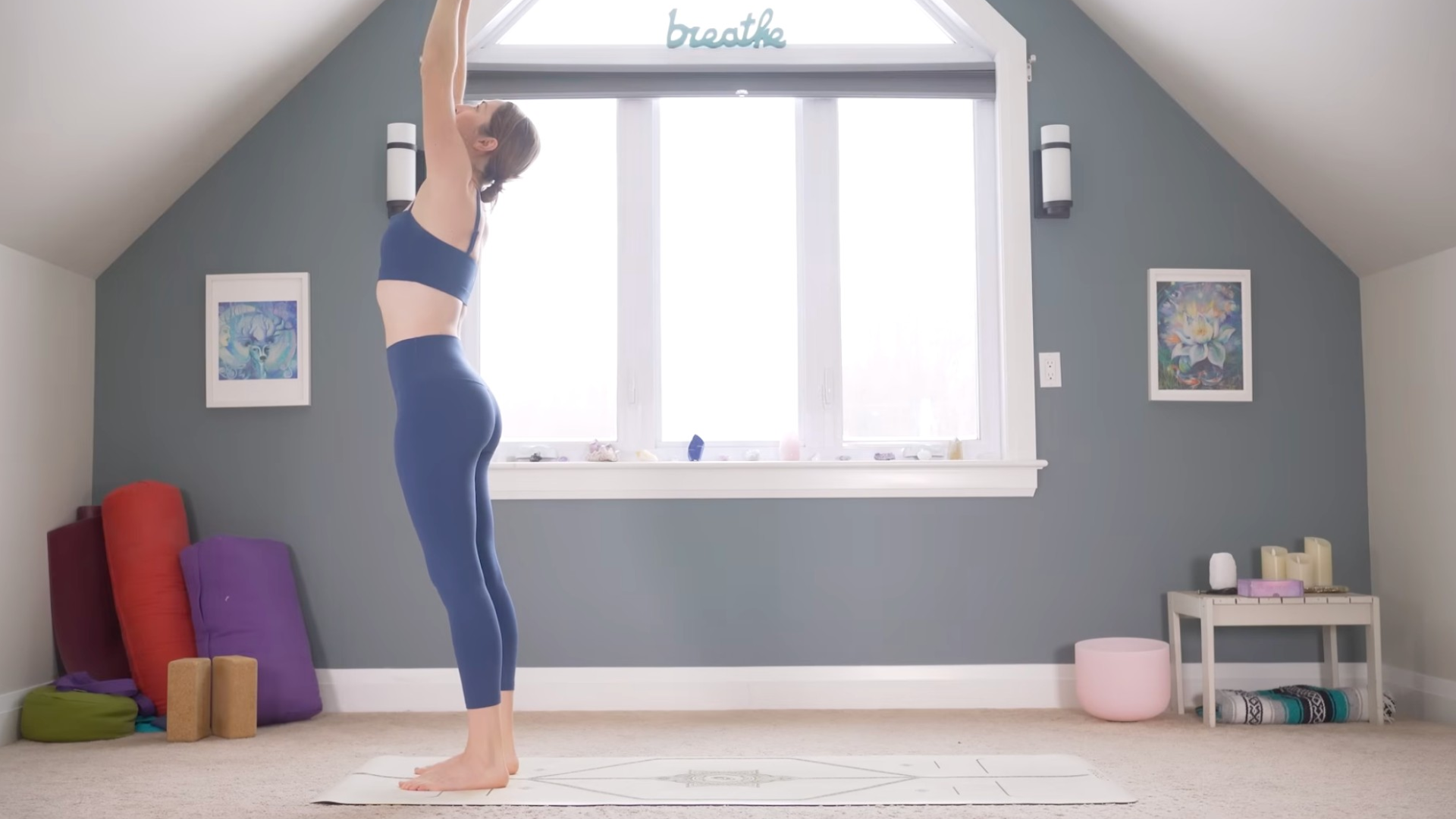 Woman standing at the front of the mat reaching her arms overhead during a 10-minute morning yoga stretches class