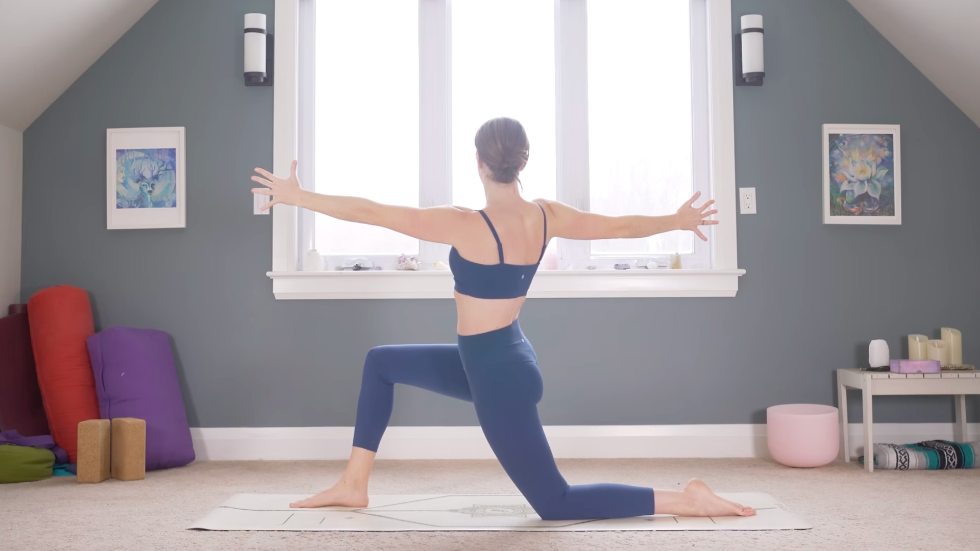 Woman kneeling on a mat in Low Lunge twisting toward the right with her arms extended straight out toward the front and back of the mat