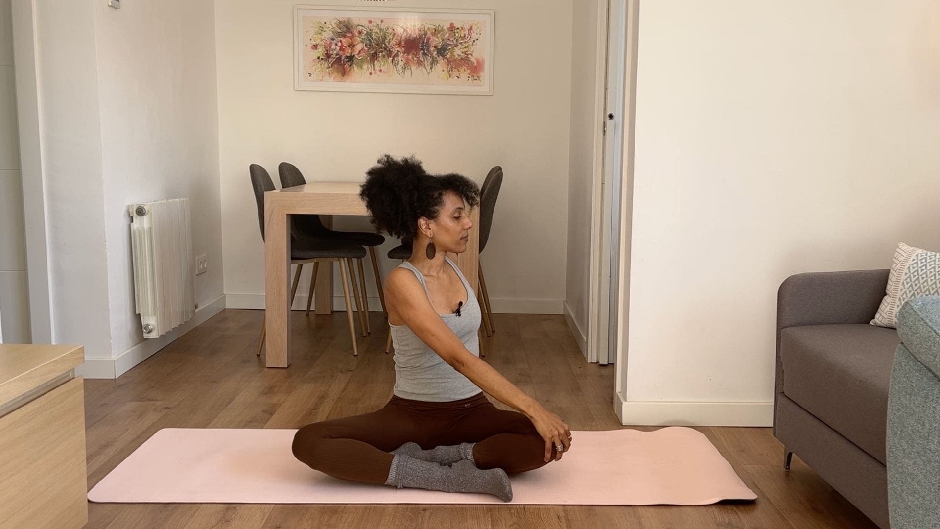 Person practicing seated spinal twist on yoga mat in living room.