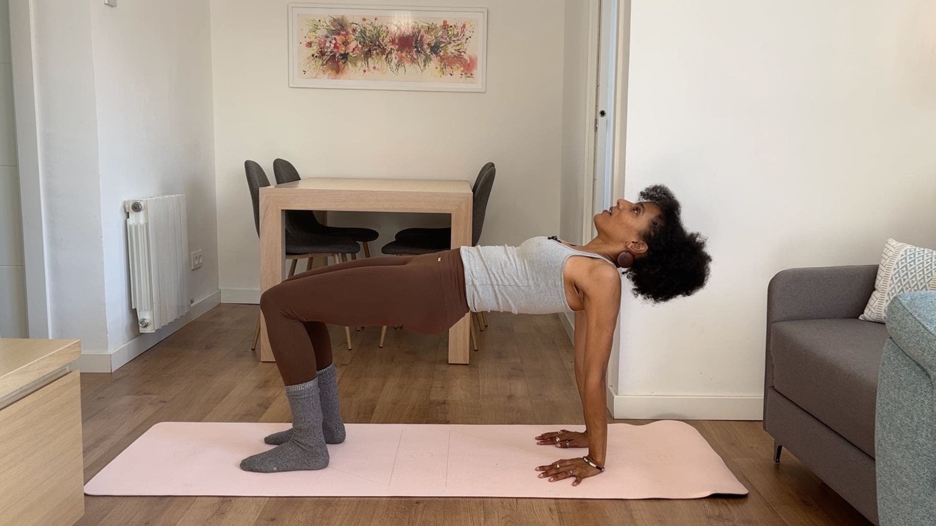 Person practicing reverse tabletop on yoga mat in living room.