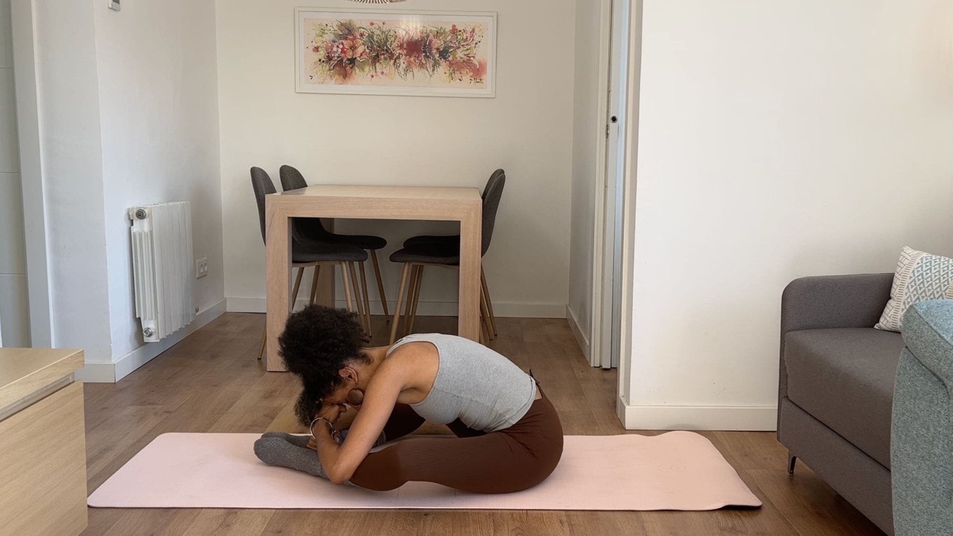 Person practicing bound angle pose on yoga mat in living room.