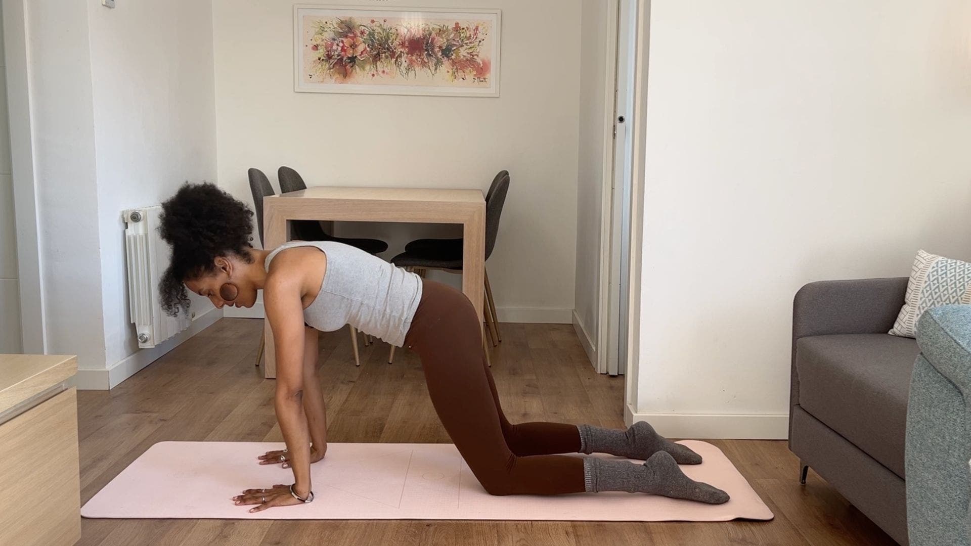 Person practicing kneeling circles on yoga mat in living room.