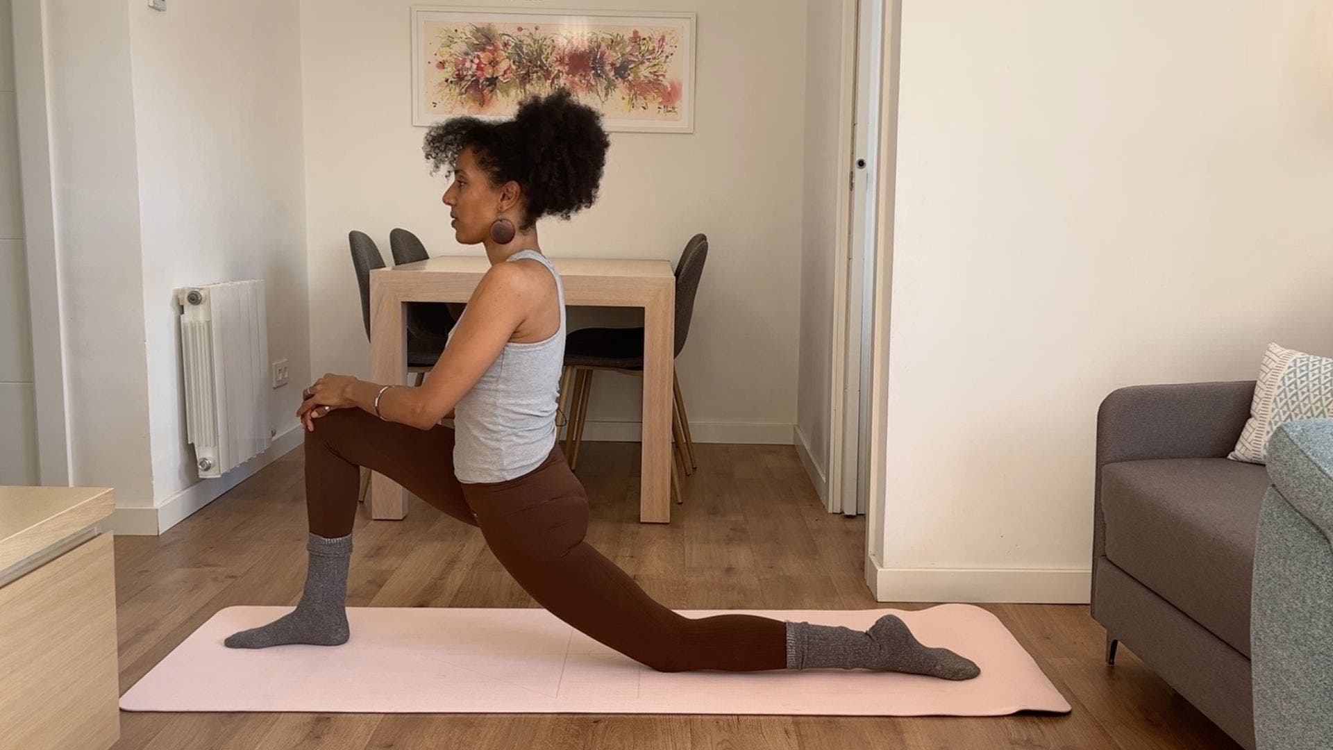 Person practicing Low Lunge on yoga mat in living room.
