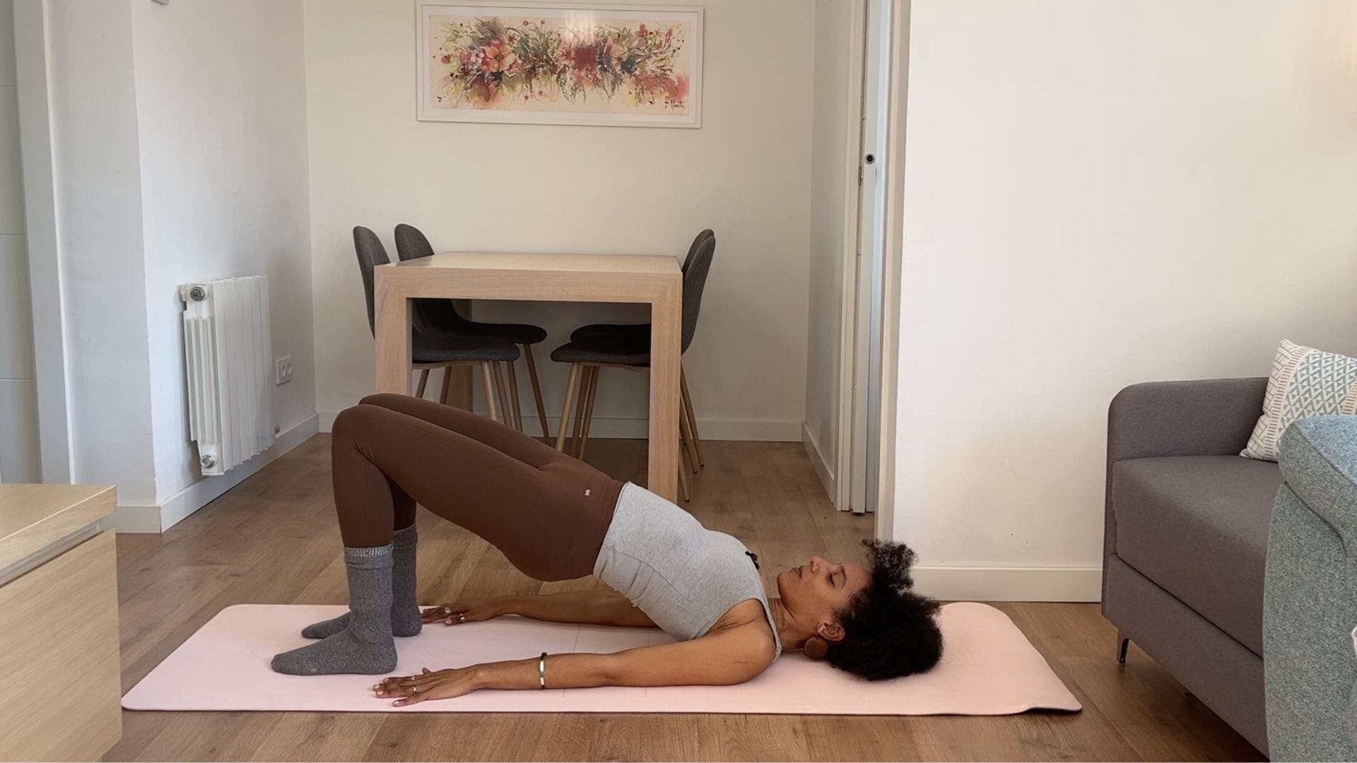 Person practicing Bridge Pose on yoga mat in living room.