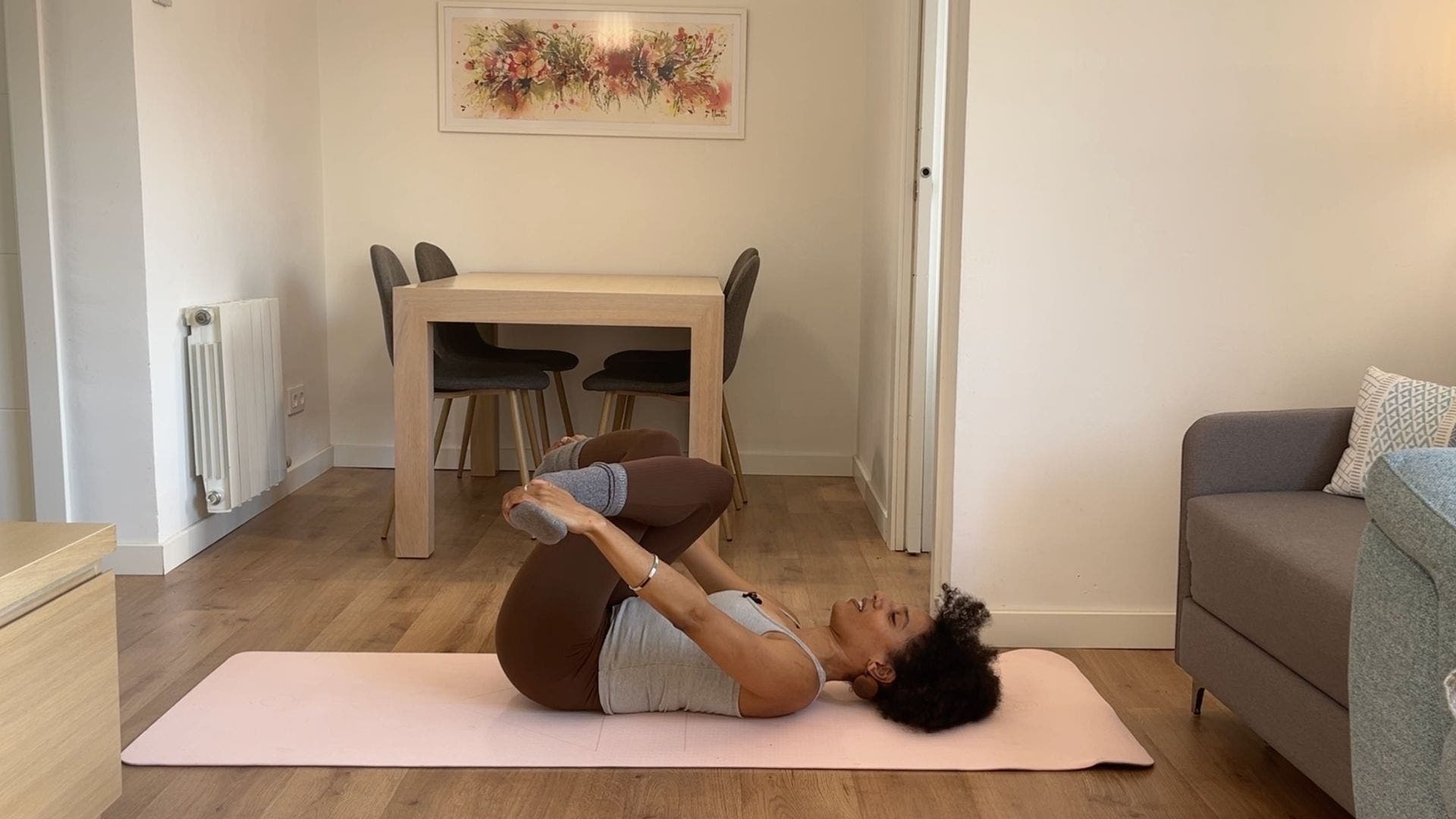 Person practicing Reclined Cow Face Pose on yoga mat in living room.