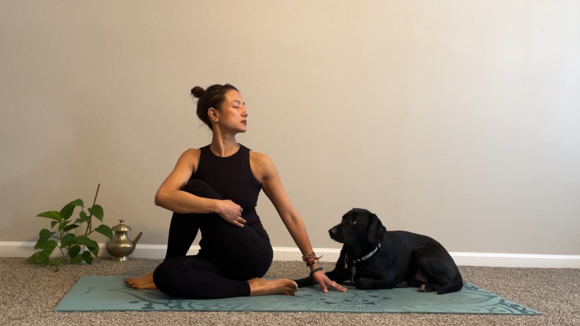 Woman sitting on a yoga mat twisting toward the left