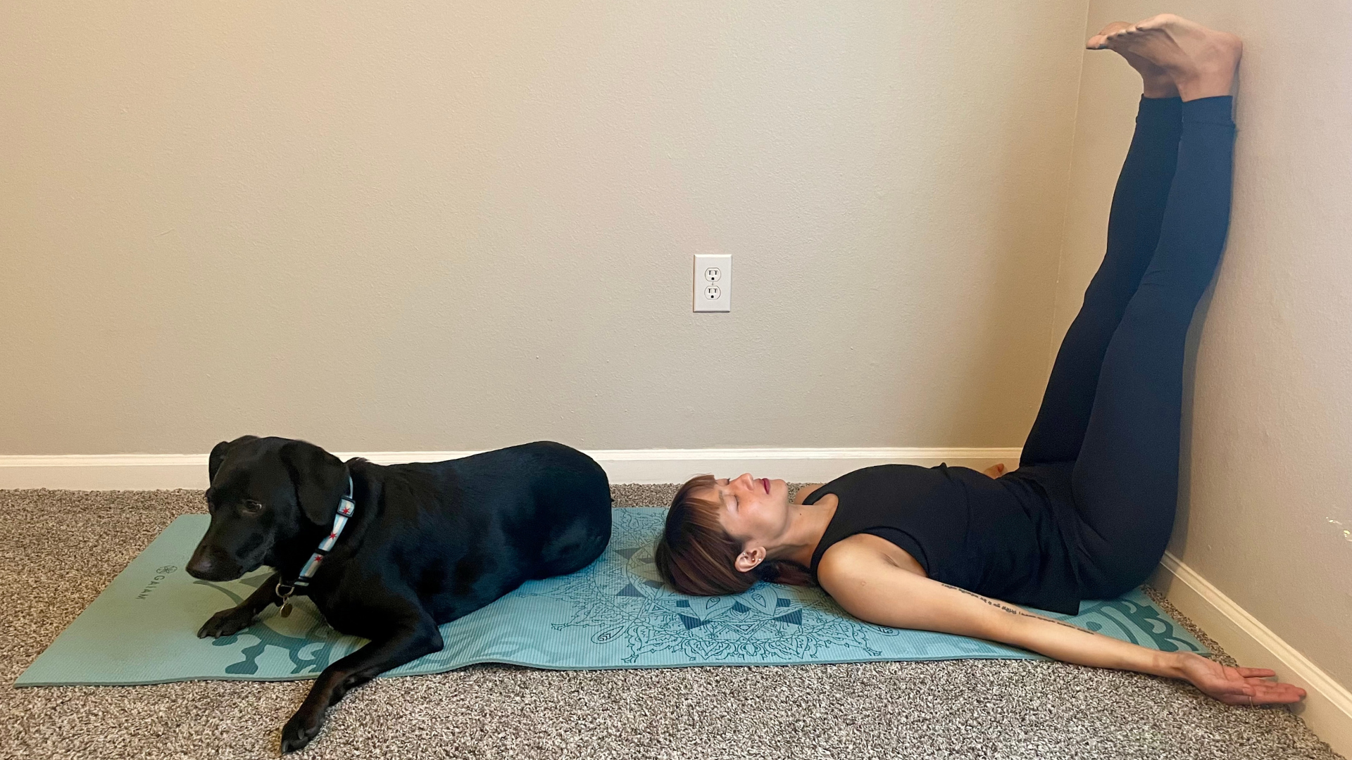 Woman lying on her back near a wall with her legs up the wall 