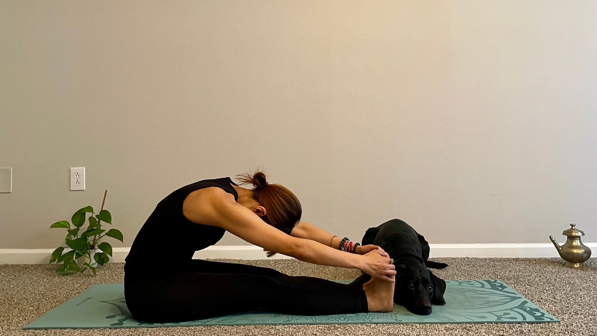 Woman sitting on a yoga mat leaning forward