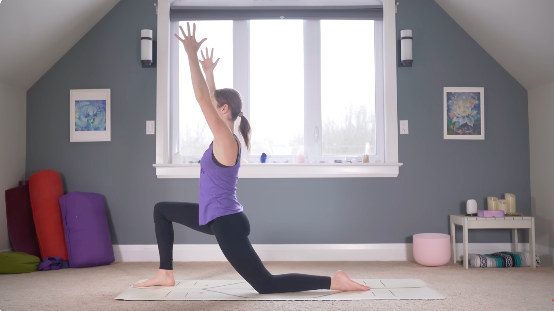 Woman kneeling on a mat in a low lunge during a 15-minute yoga for beginners class with her arms reached alongside her head