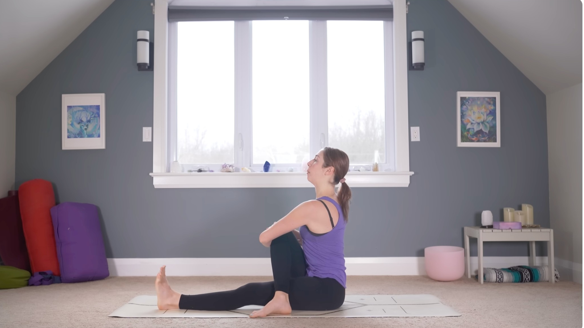 Woman sitting on a mat about to do a twist during a 15-minute yoga for beginners class