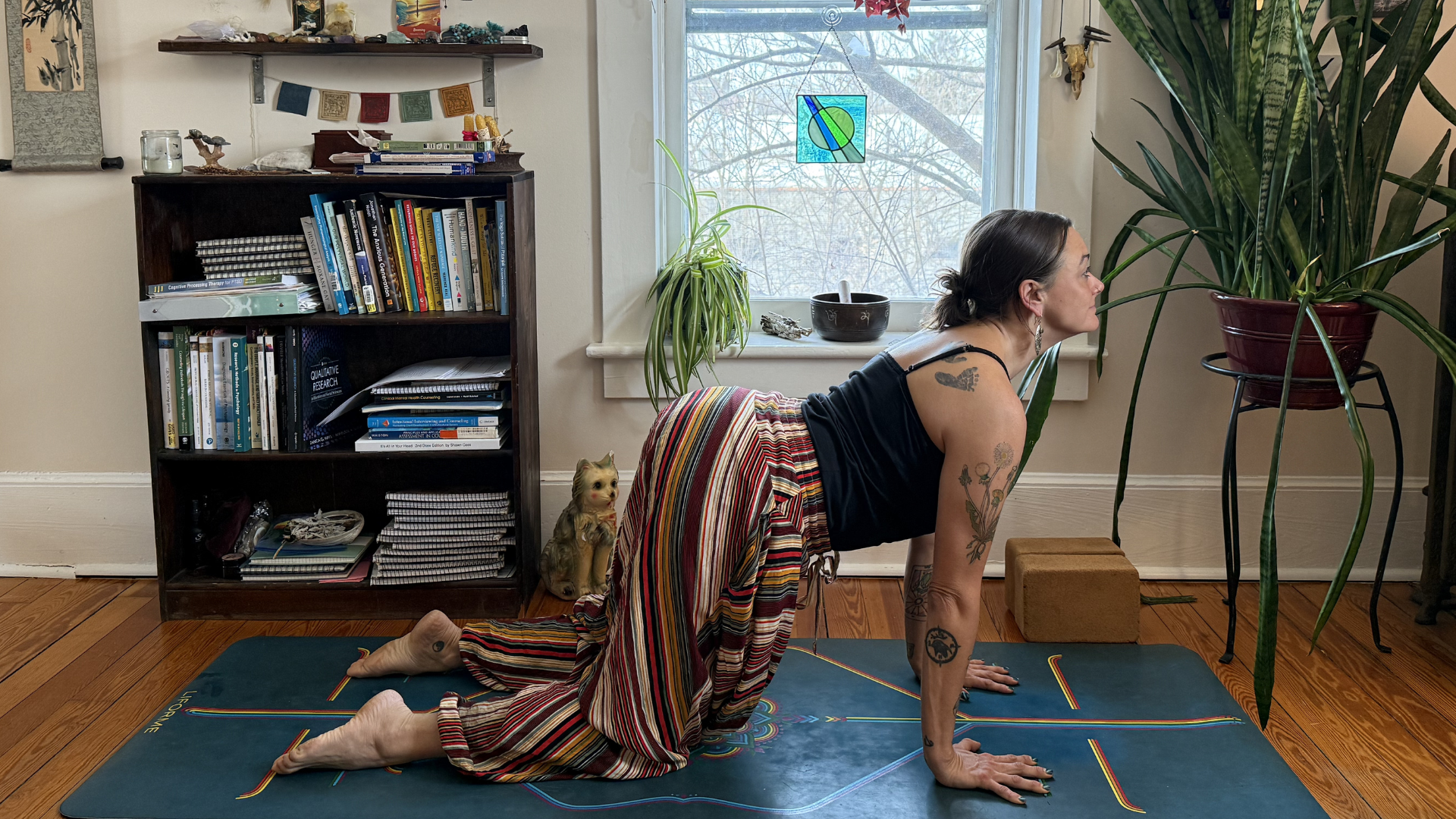 Woman on her hands and knees on a mat practicing Cow Pose, a yoga for courage practice