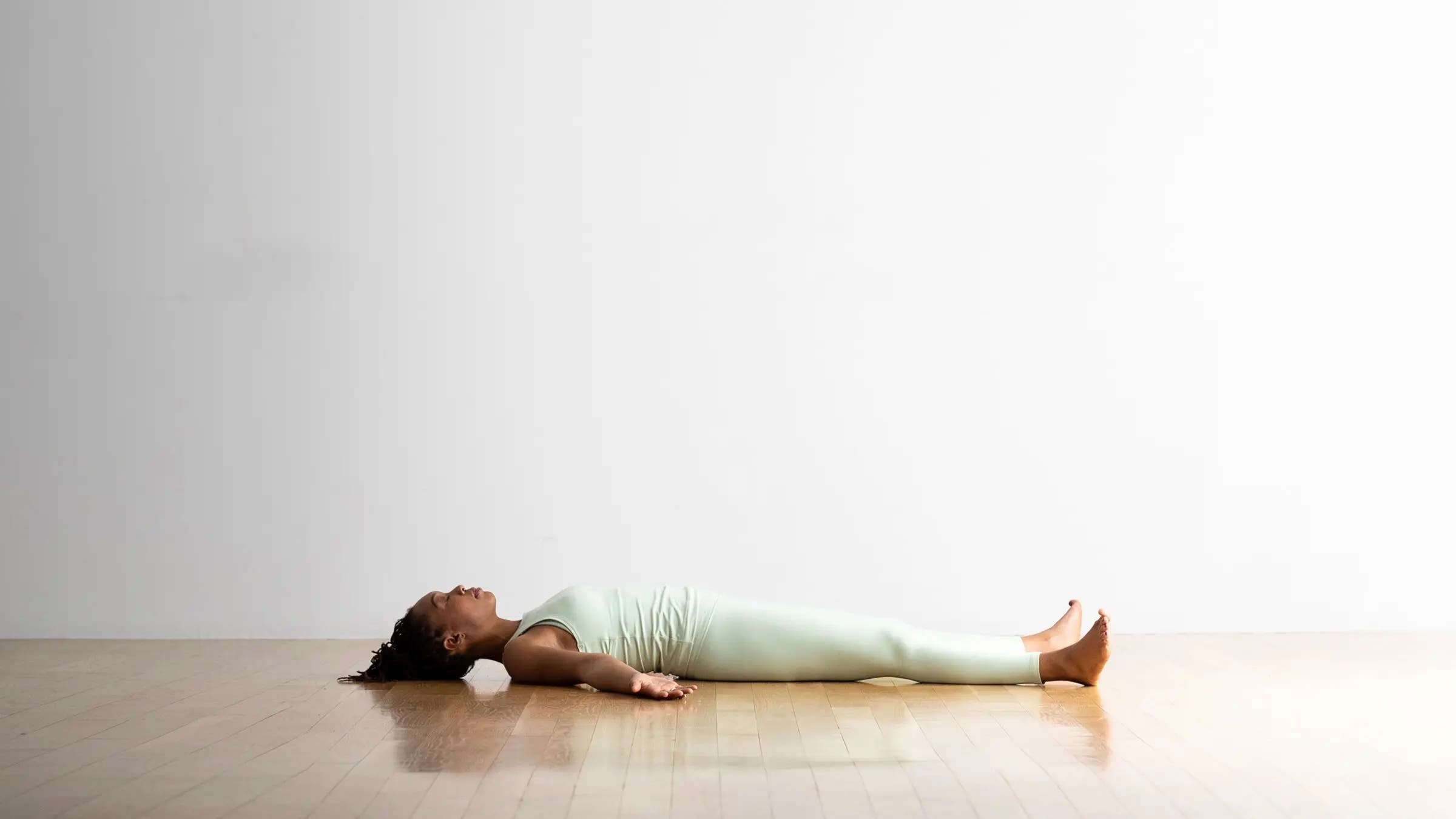 A woman lying in Savasana, one of our favorite yoga pose for anxiety