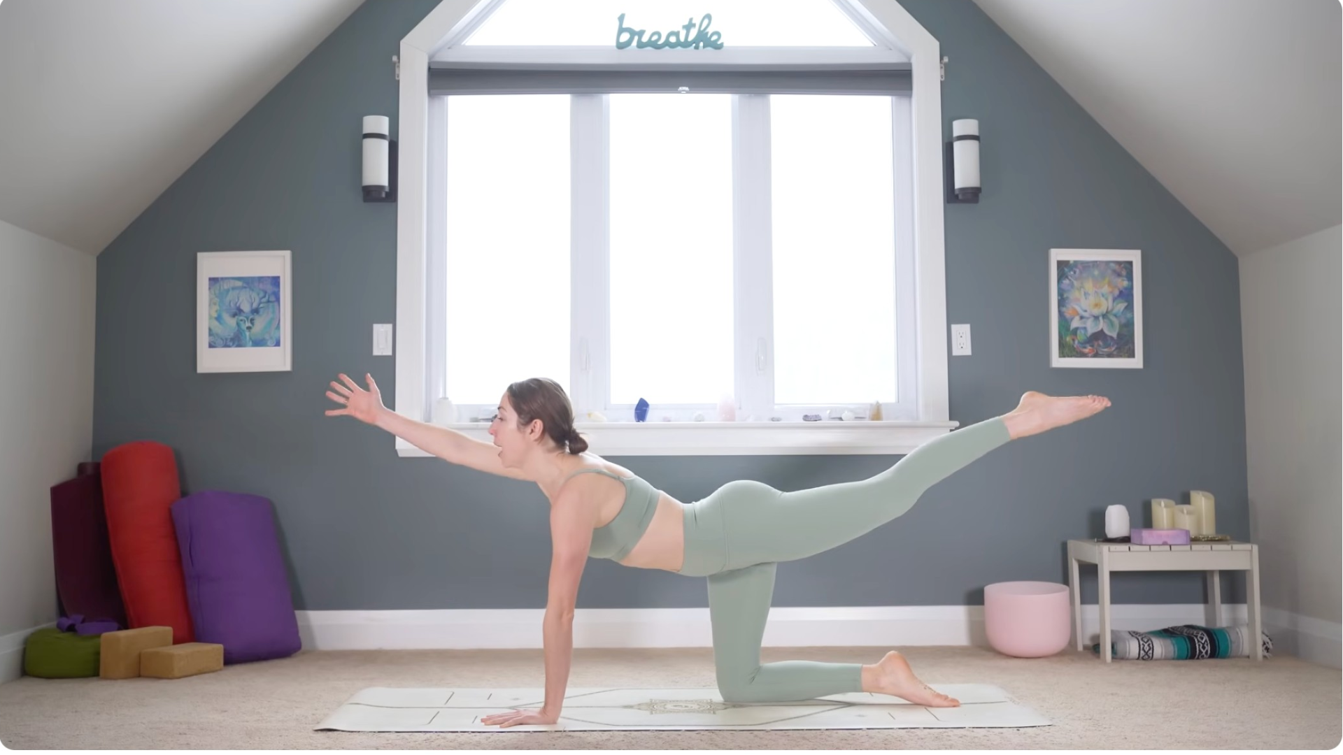 Woman kneeling on a mat reaching her right arm and left leg out straight