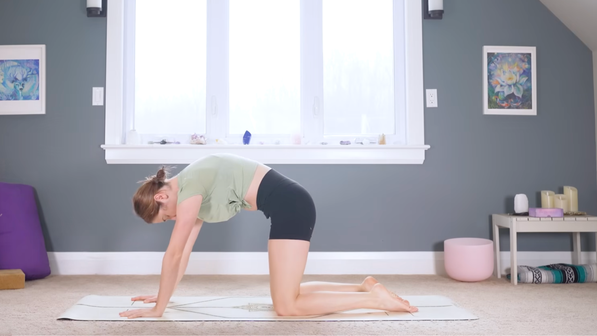 Woman kneeling on hands and knees with her back rounded and the back of her neck long