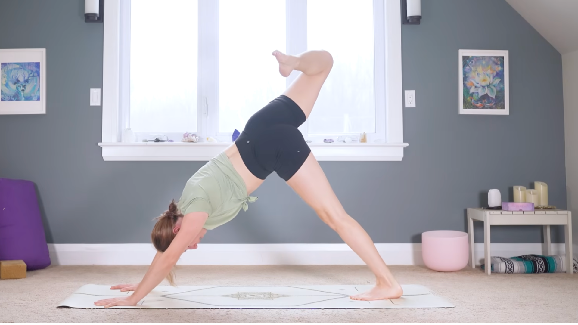 Woman on a mat in a variation of Downward-Facing Dog with one leg lifted and her knee bent