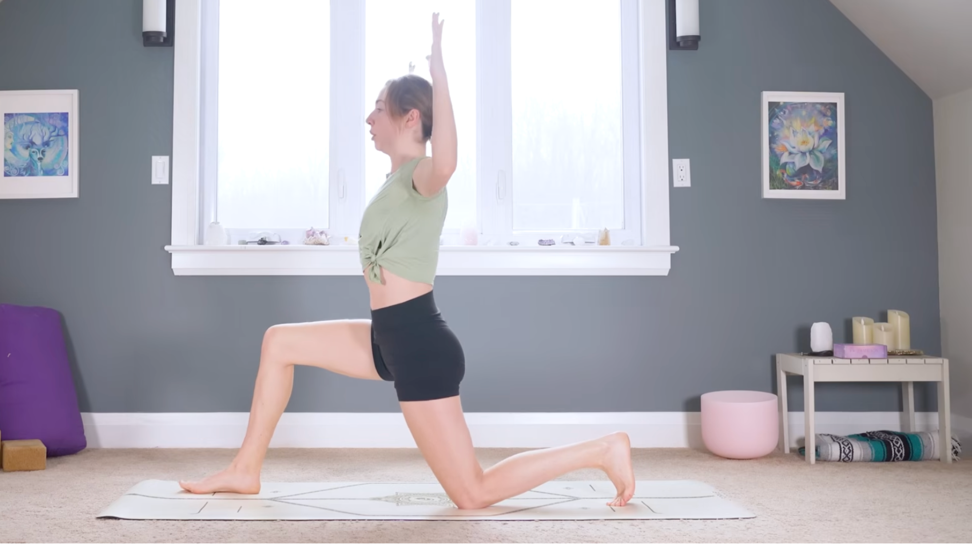 Woman kneeling on a mat in Low Lunge with her arms alongside her head in a cactus shape