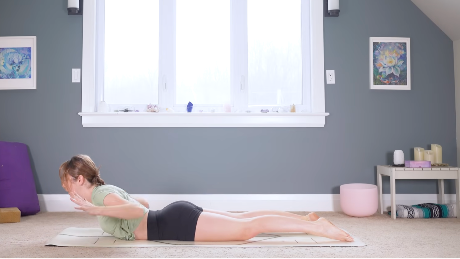 Woman lying on her belly on a mat while lifting her chest and hands