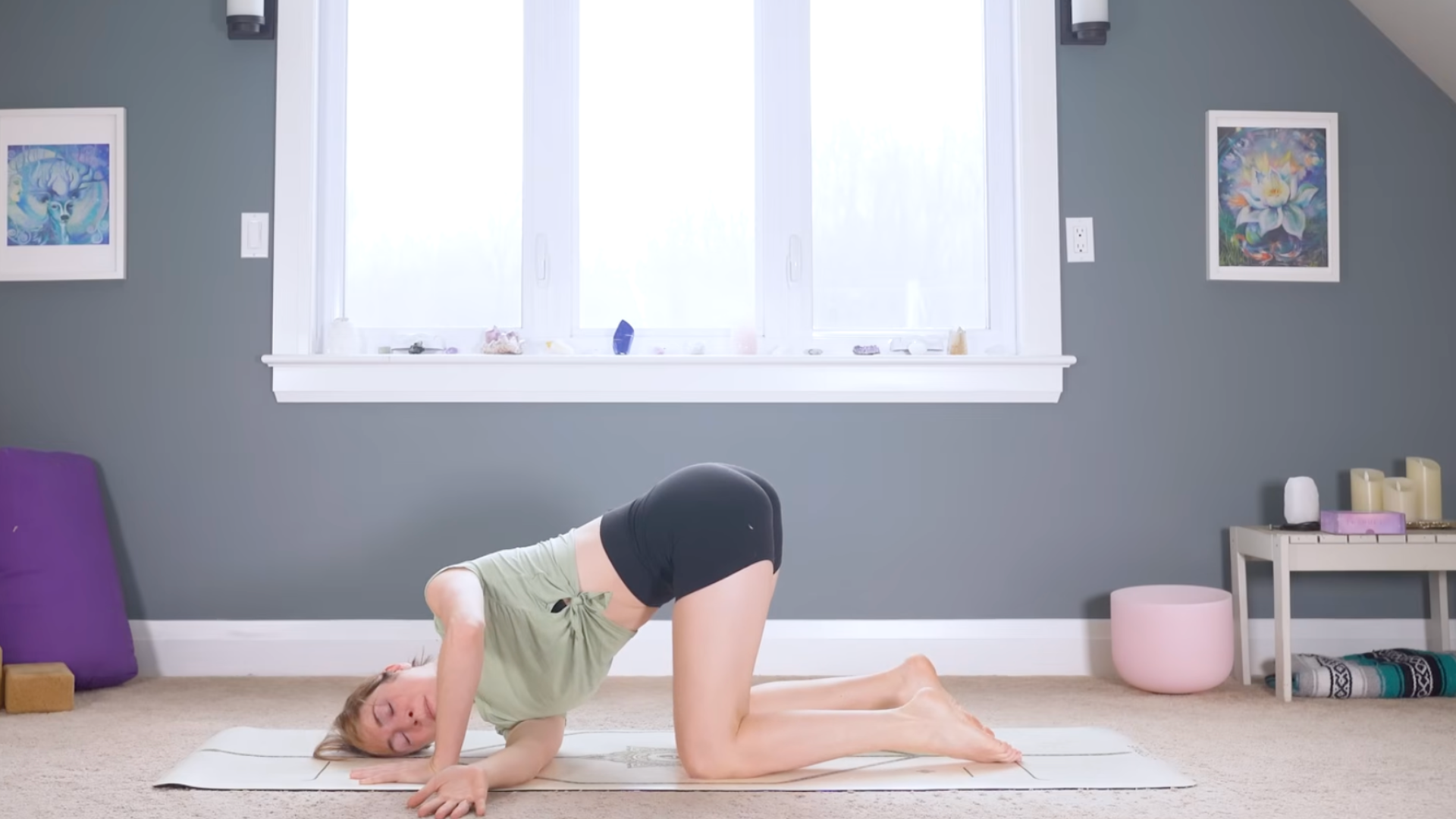 Woman kneeling on a mat and reaching her right arm beneath her chest in Thread the Needle during a 10-minute morning yoga for back practice