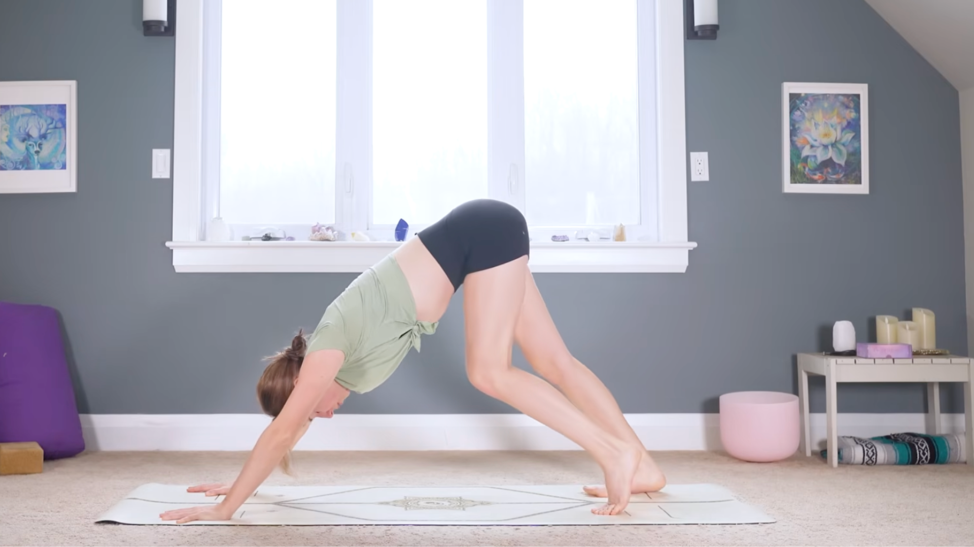 Woman in Downward-Facing Dog on a mat with one knee bent
