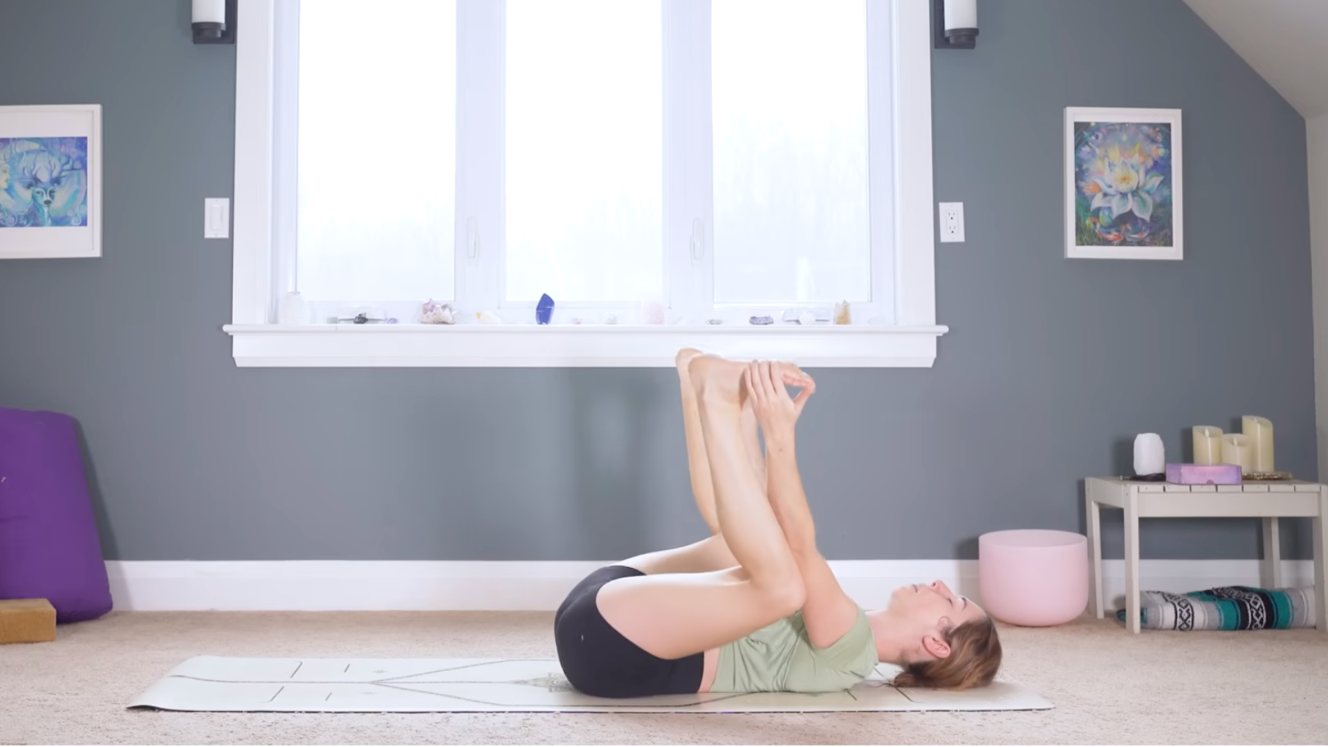 Woman lying on her back with her knees bent and her hands on her feet