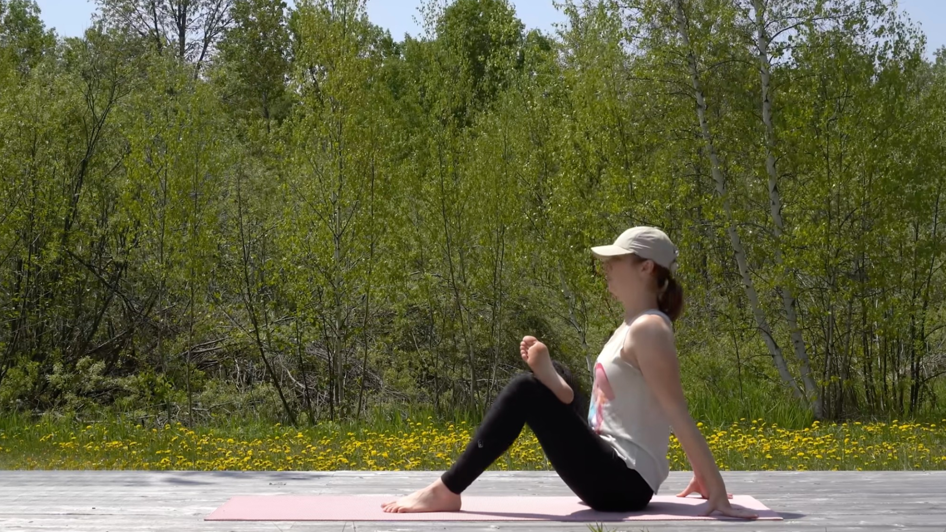 Woman sitting back on a yoga mat with one ankle crossed over the opposite knee during a hip-opener stretch