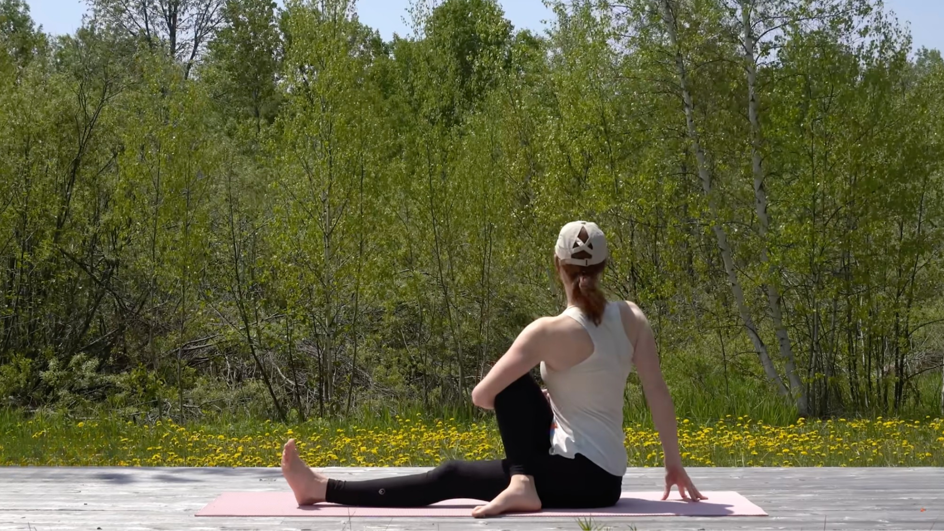 Woman sitting on a mat twisting toward the right with one leg straight and the other knee bent in a 10-minute morning yoga routine