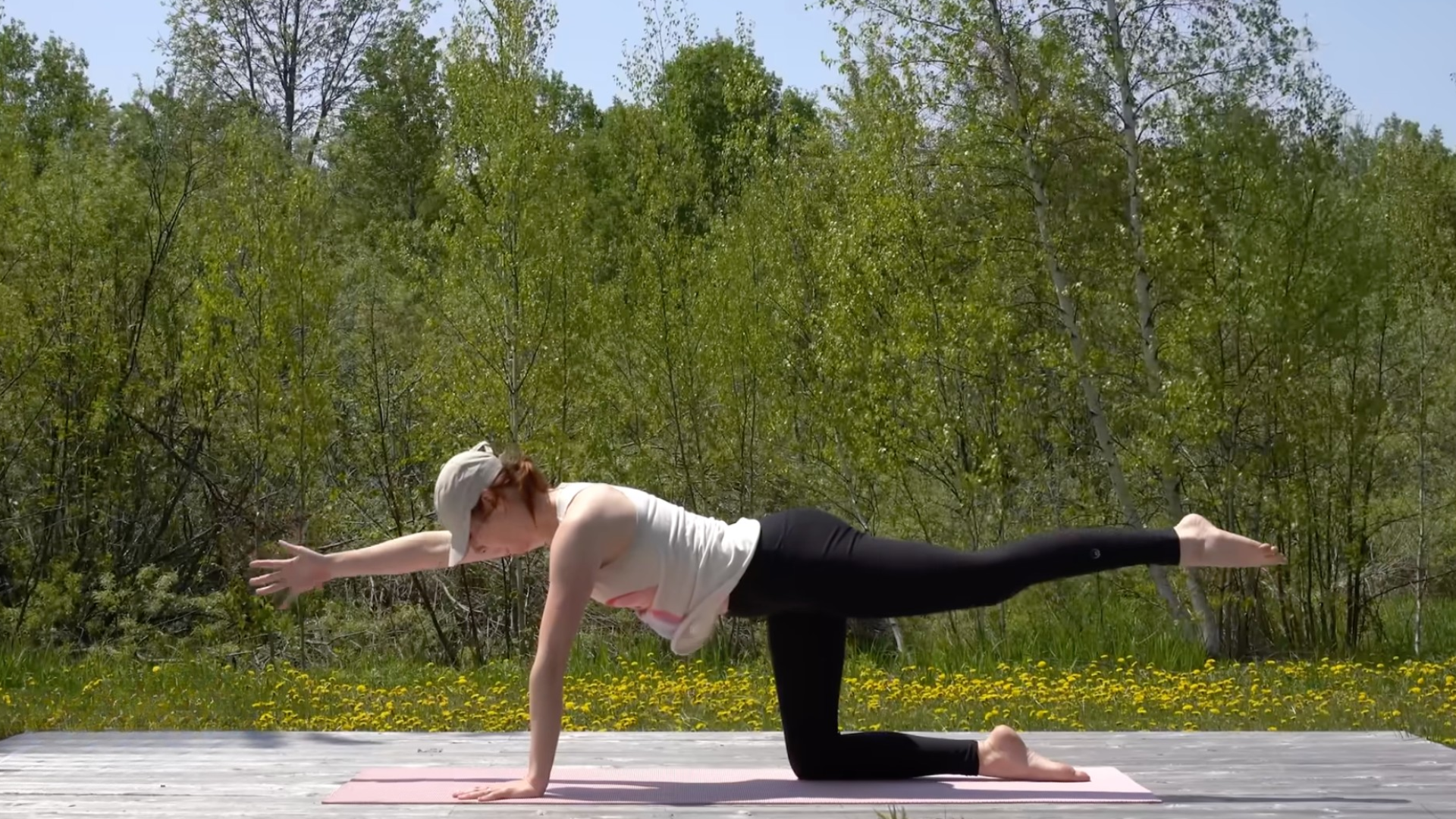 Woman kneeling on a mat with her left leg reaching behind her and her right arm reaching forward