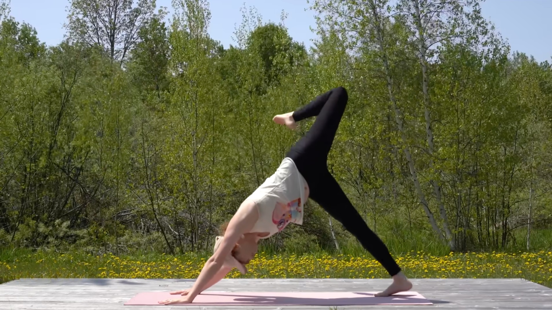 Woman practicing a 10-minute morning yoga routine in Three-Legged Dog with her right leg lifted and her knee bent in a hip stretch