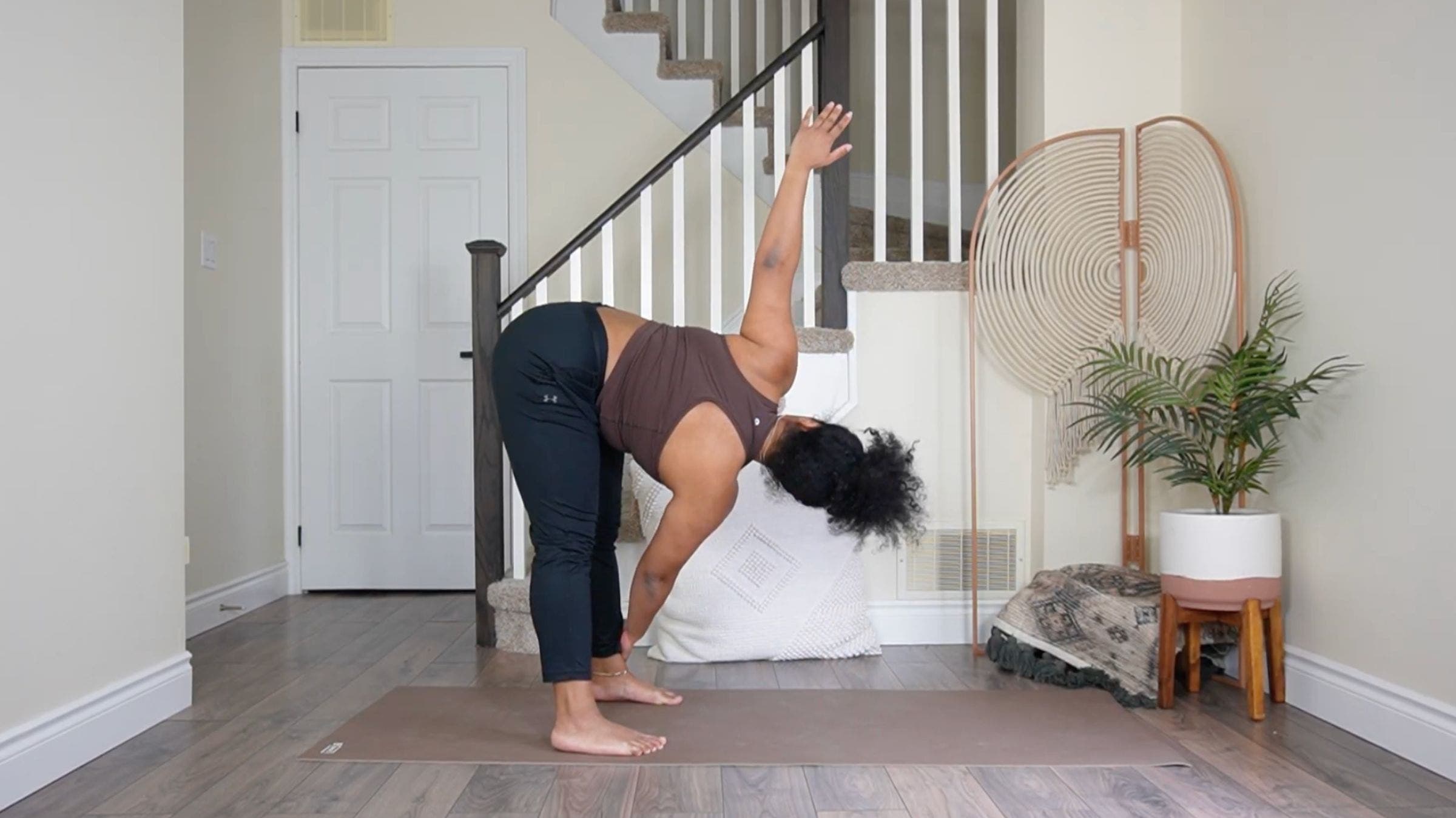 Yoga teacher practicing Revolved Standing Forward Bend.
