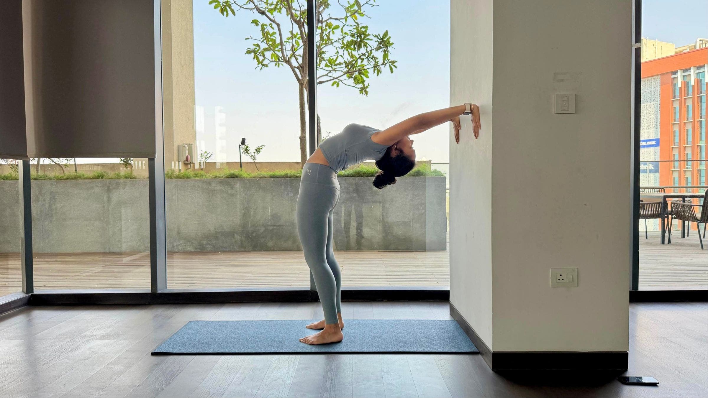 Riya Davda practicing Wheel Pose variation against wall.