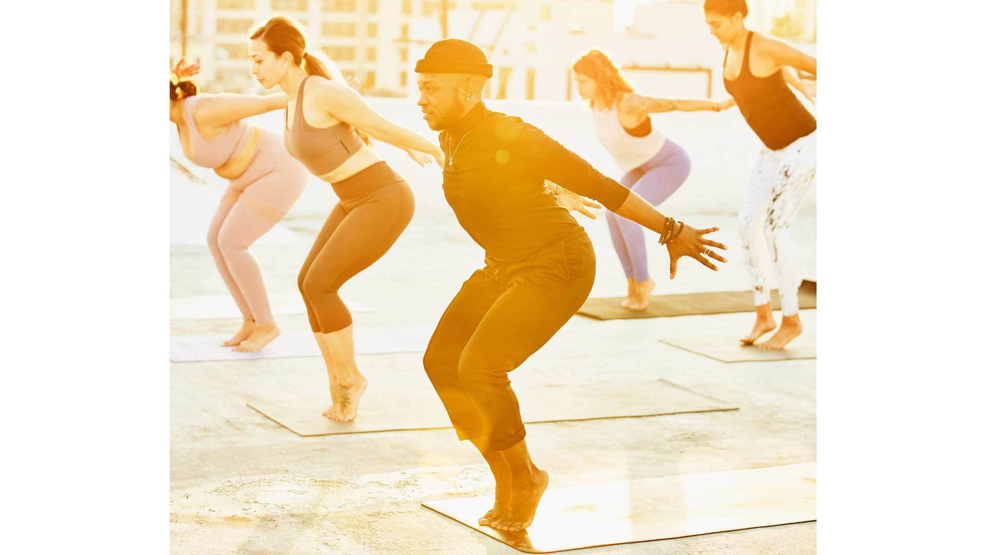 Students in a yoga class practicing balancing exercises by coming into Chair Pose and lifting their heels