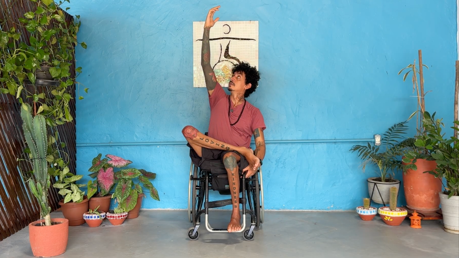 Yoga teacher in a wheelchair while reaching his right arm overhead in a side bend