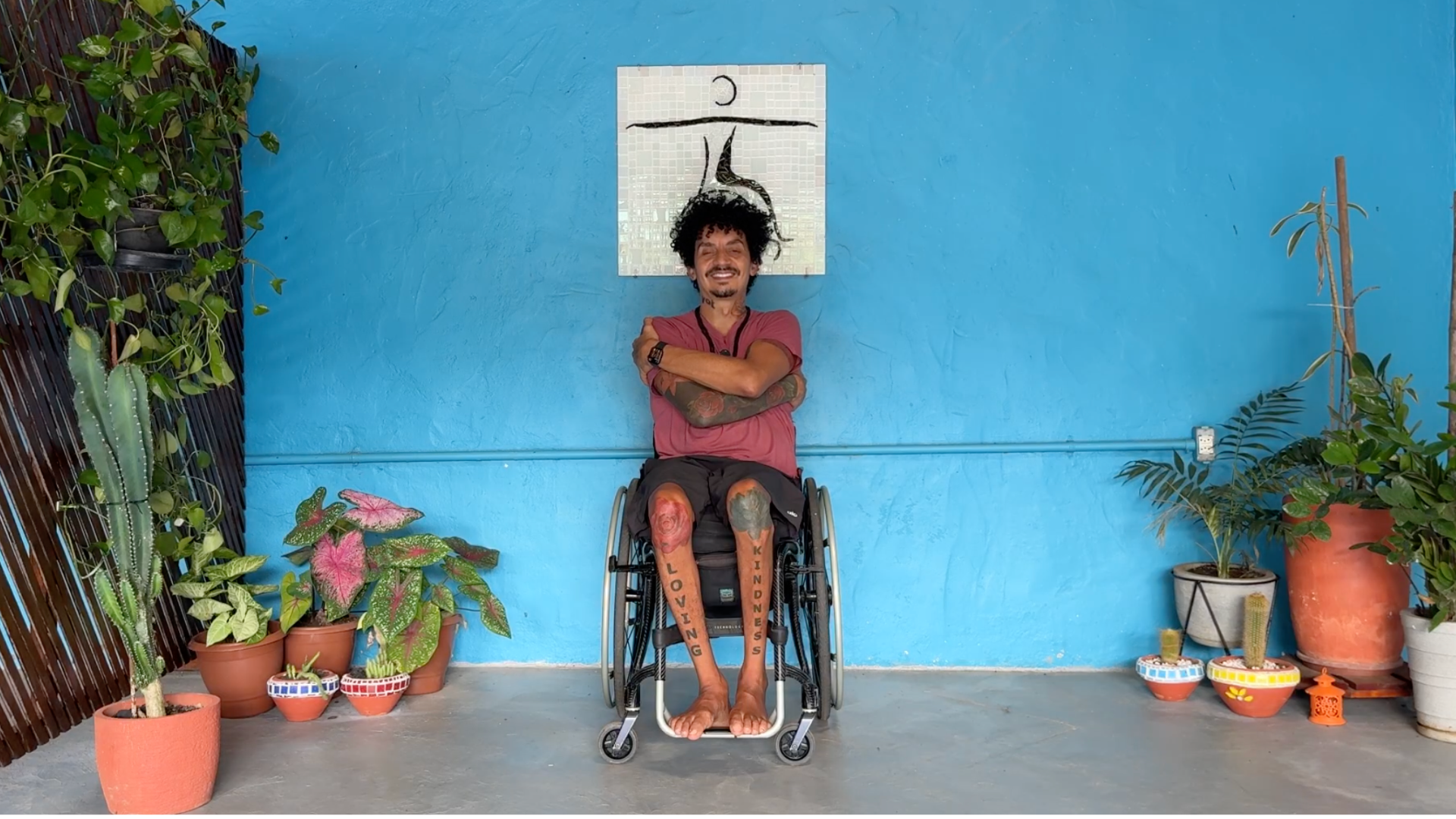 Teacher leading an adaptive chair yoga challenge class with his arms wrapped around himself