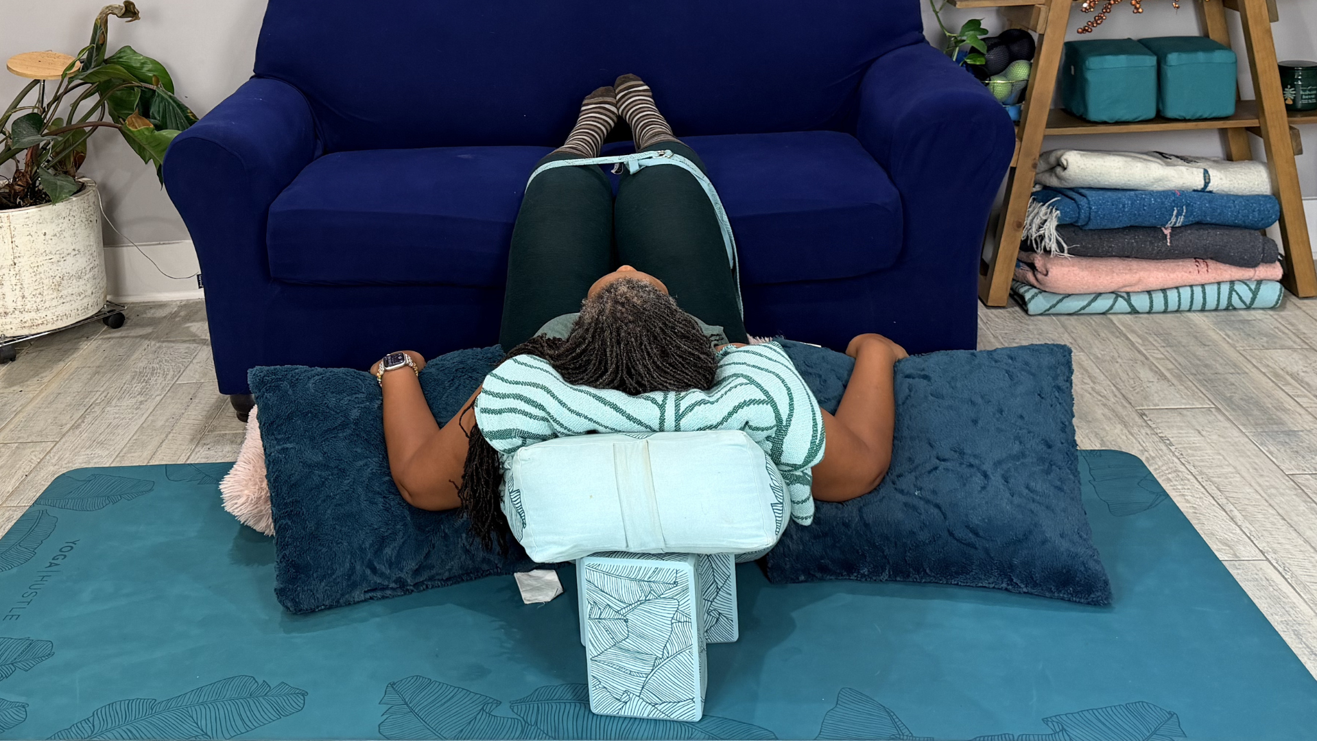 Woman practicing restorative yoga for calm while relaxing with her back on a bolster