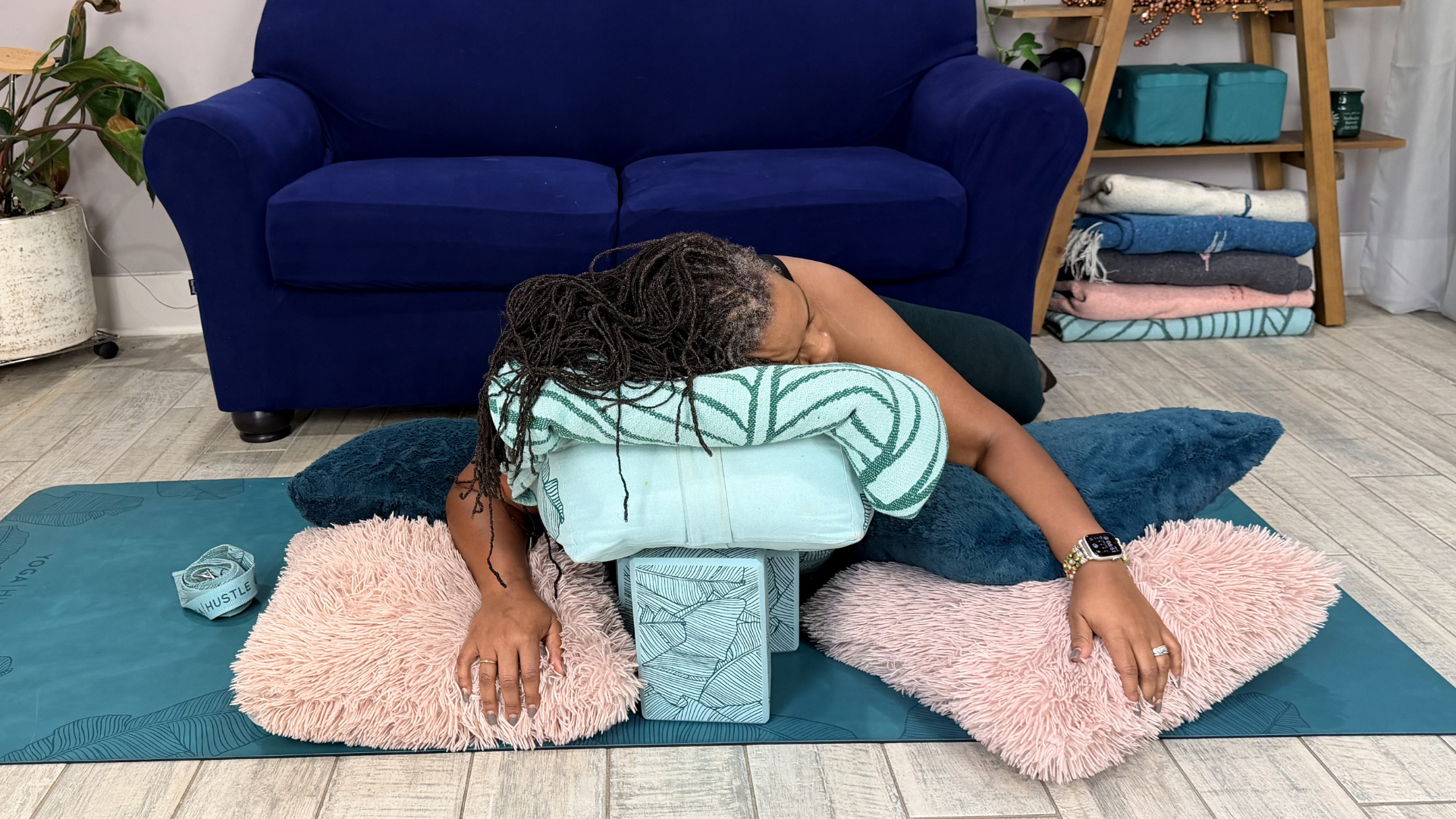 Woman lying on a stack of bolsters and pillows practicing restorative yoga