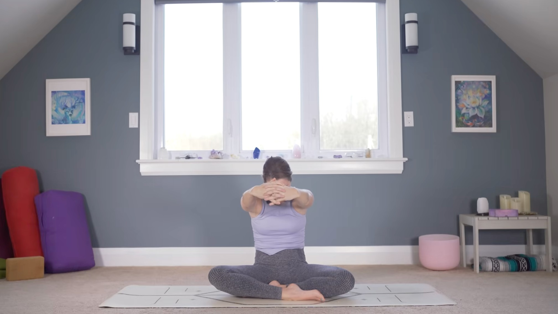 Woman sitting on a mat reaching her arms forward in a shoulder stretch