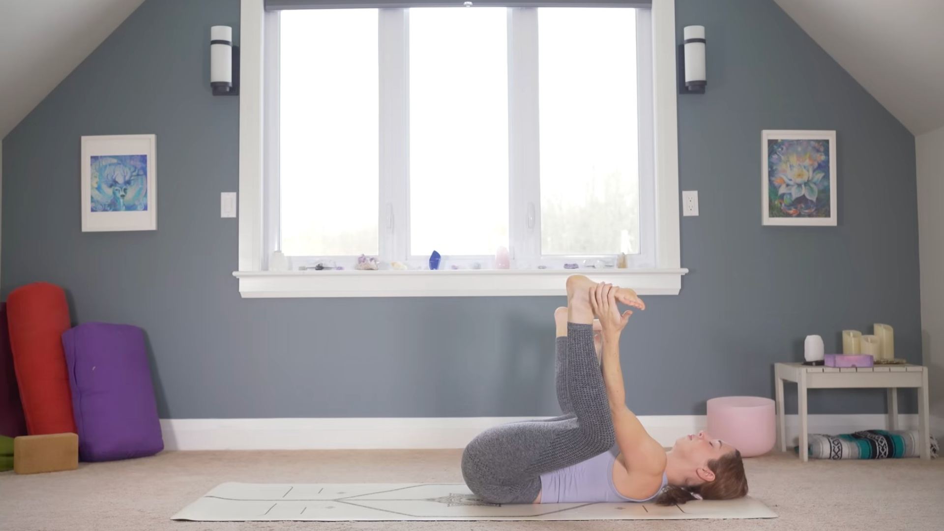 Woman lying on her back with her hands on her feet in Happy Baby Pose