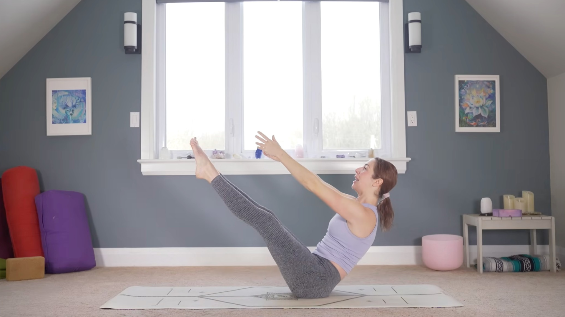 Woman on a mat with her arms and legs reaching in Boat Pose