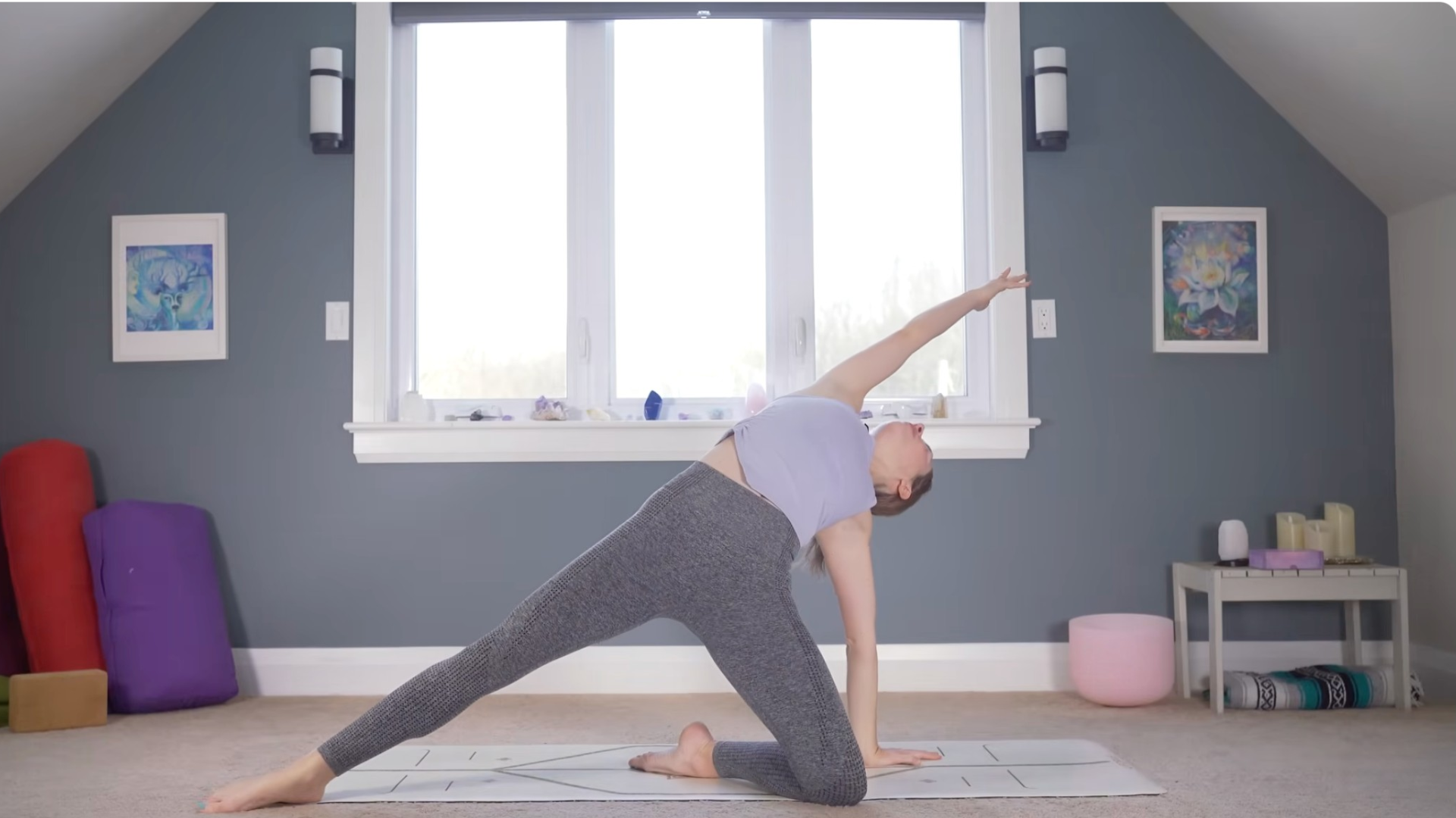 Woman kneeling on a mat with one arm reaching alongside her head in Baby Wild Thing