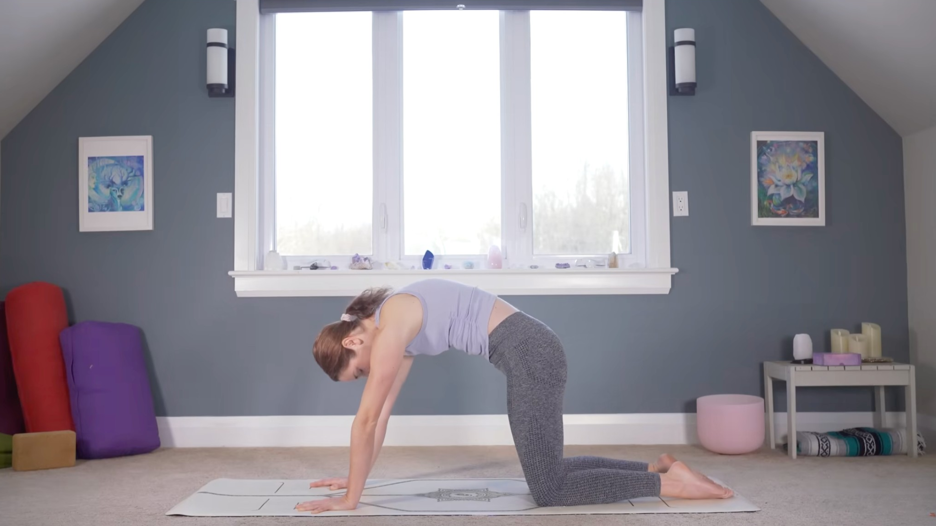 Woman kneeling on a yoga mat rounding her back
