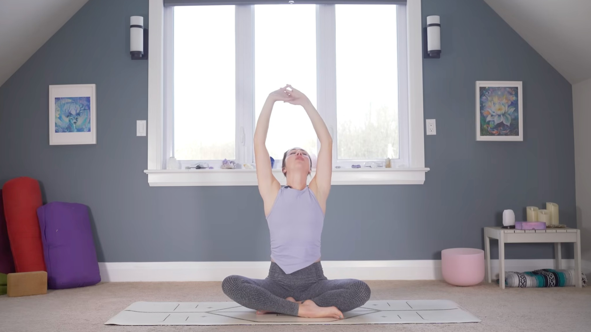 Woman sitting on a mat stretching her arms alongside her head