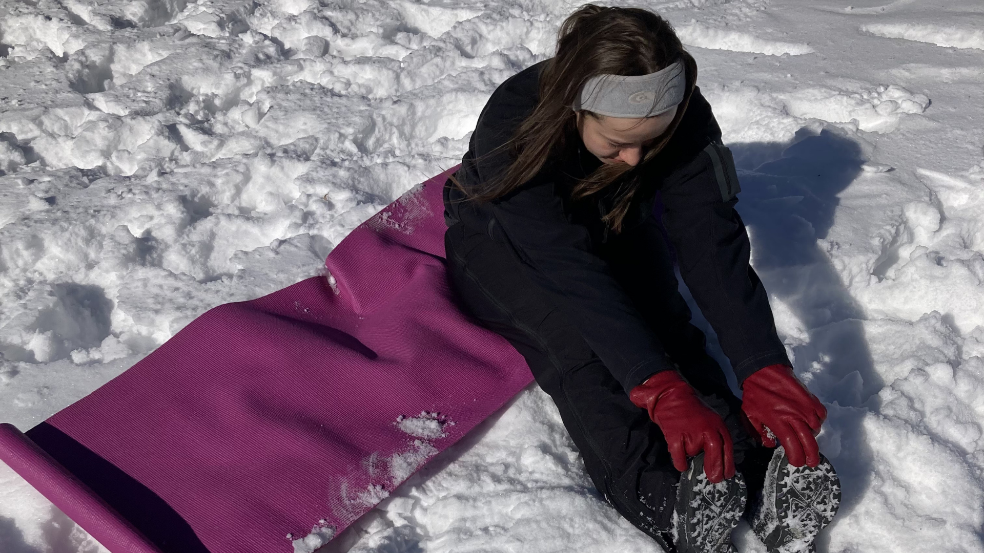 Woman sitting on a yoga mat while practicing snowga in Canada