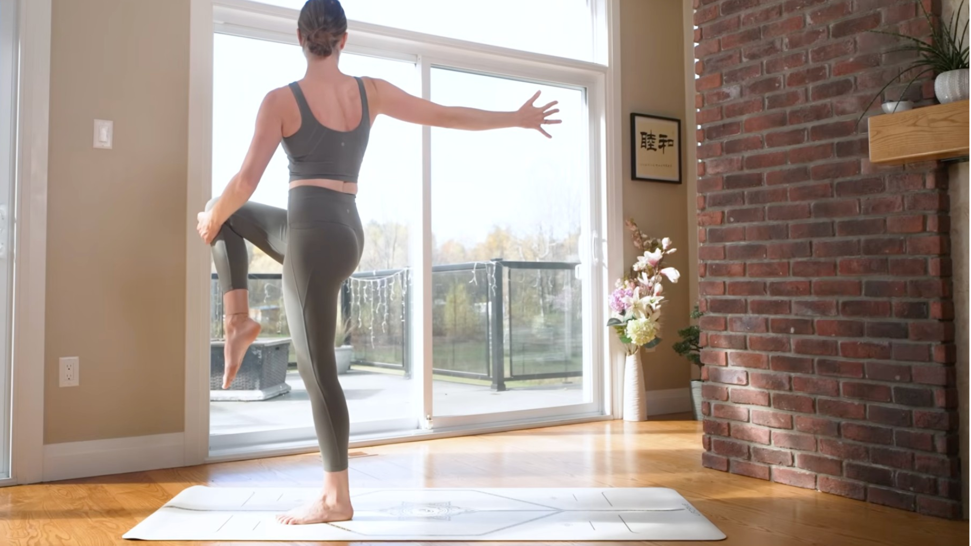 Woman doing standing yoga as she twists toward the right and reaches her right arm back