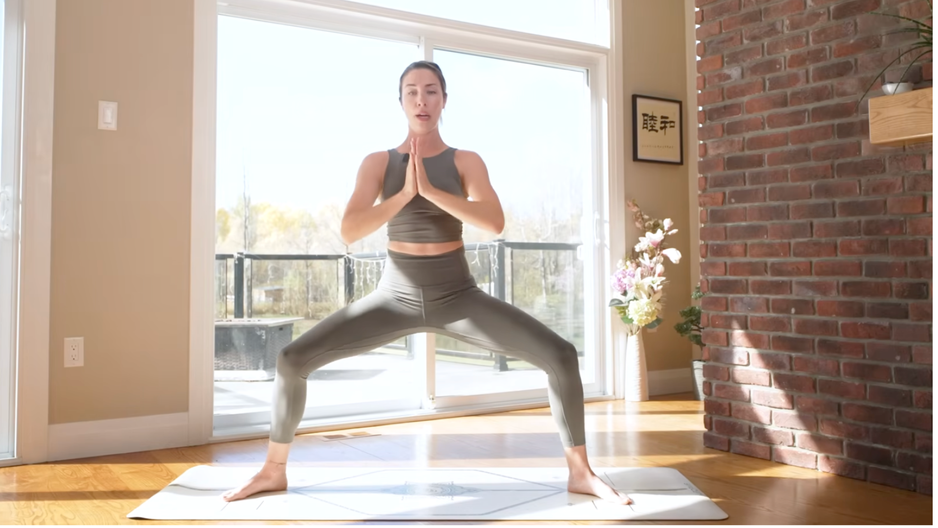Woman with her knees bent and her hands at her chest in Goddess Pose