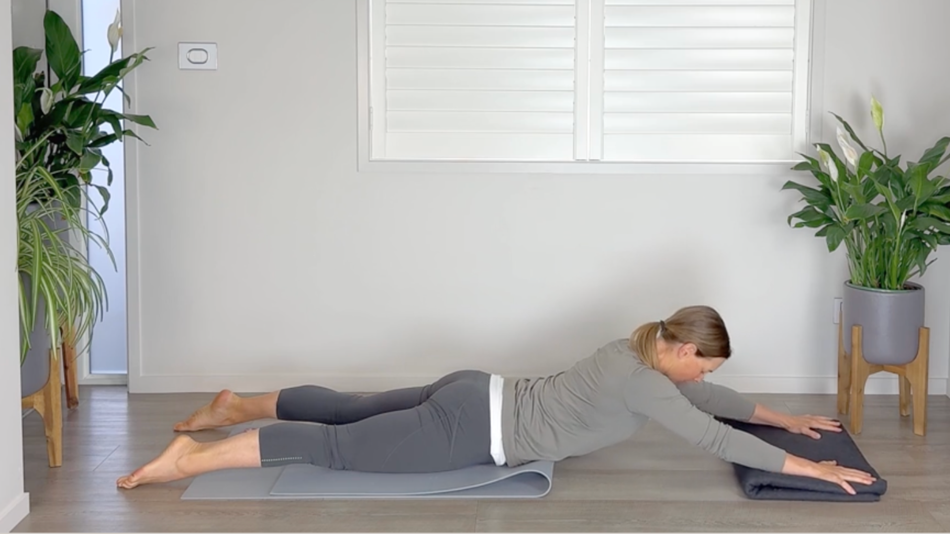 Woman lying on her stomach with both hands on a folded blanket