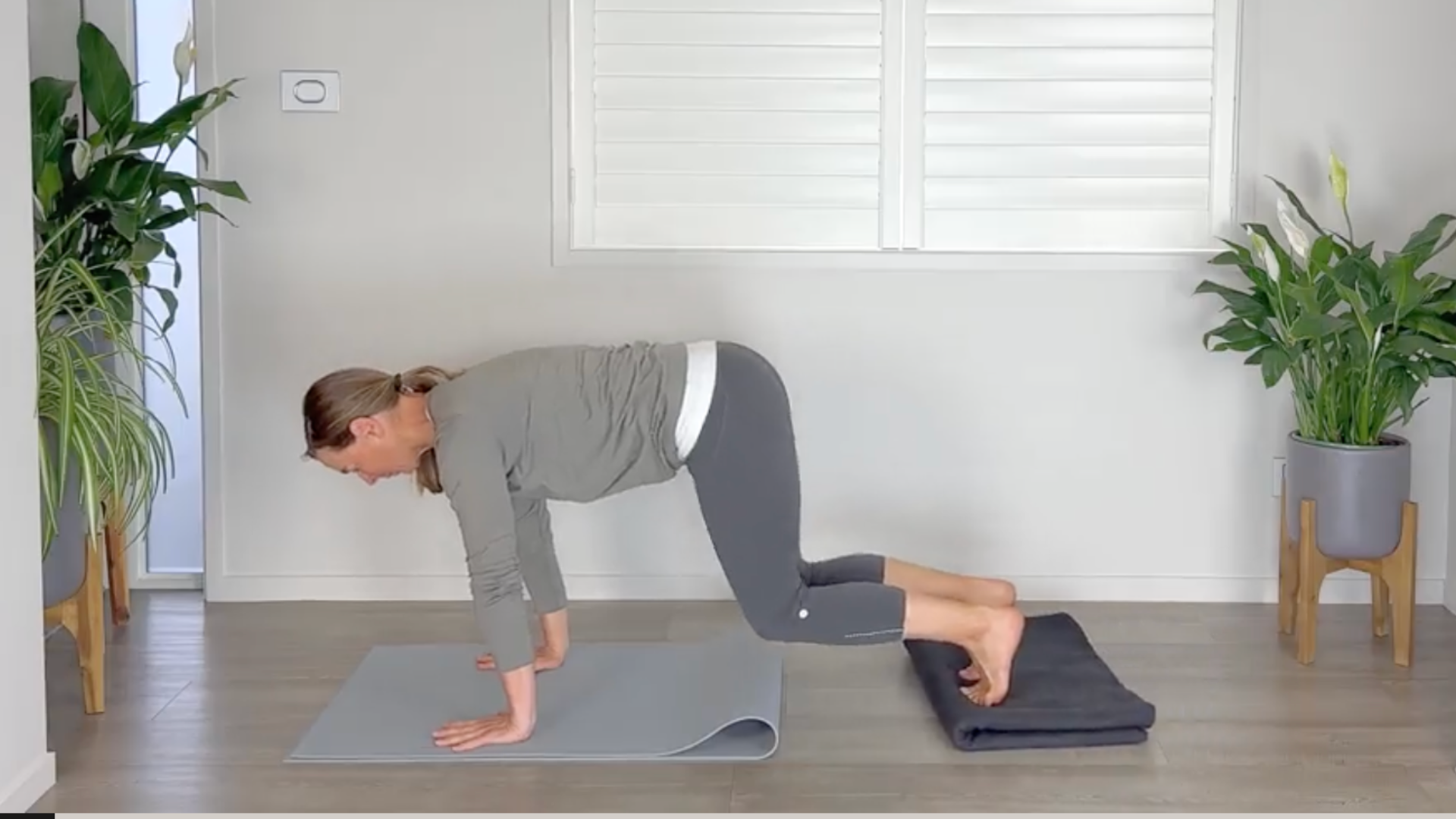 A woman rests her feet on a yoga blanket while practicing plank pose
