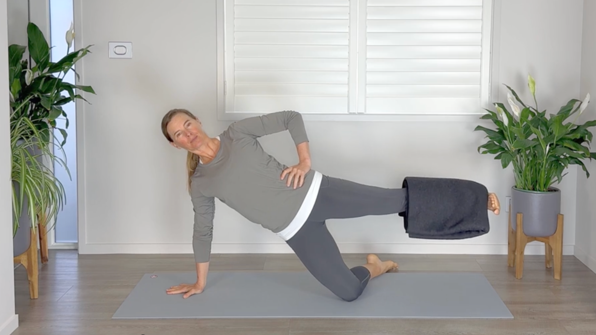 A woman kneels on one side and raises her other leg