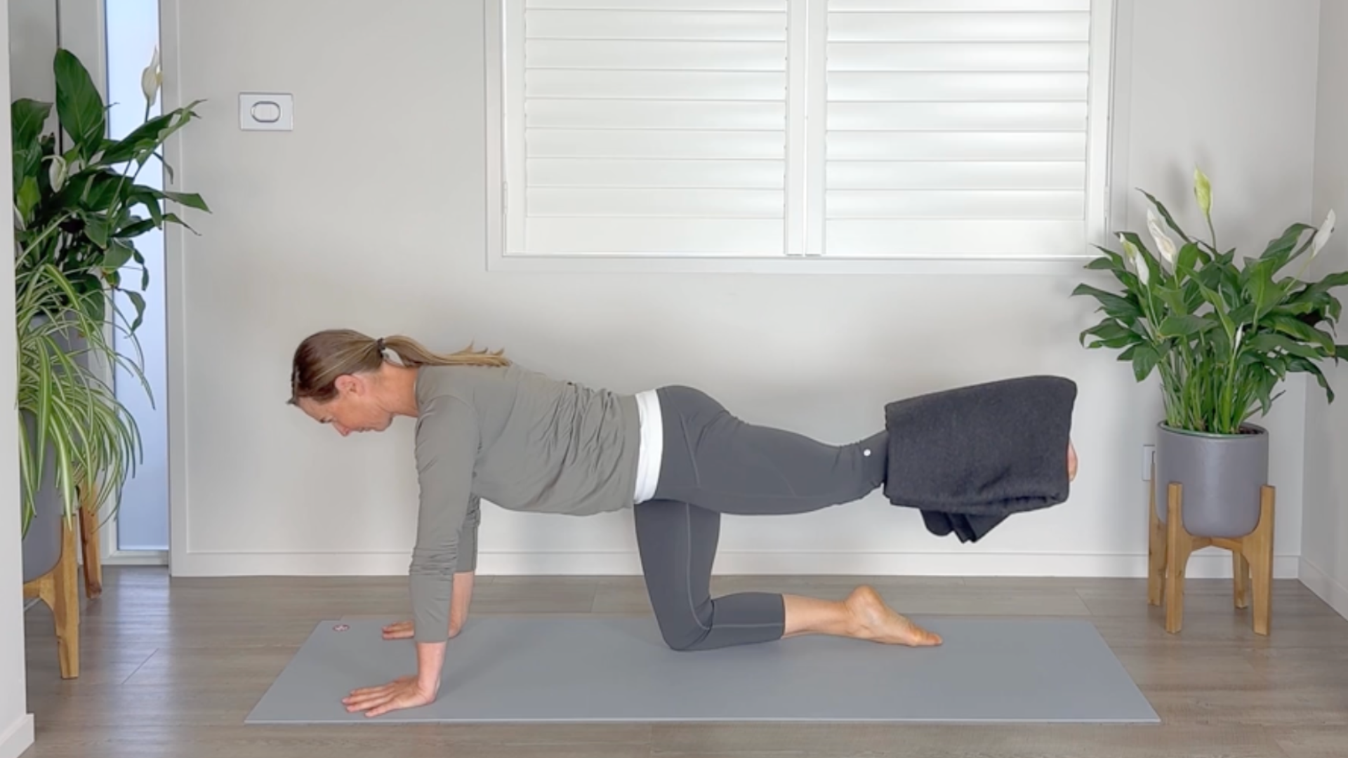 Woman on hands and knees on mat with her back leg raised